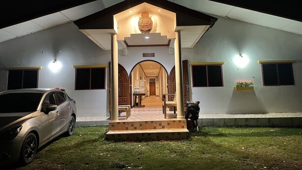 A building with a covered entrance, a car parked in front, and a motorcycle to the side. - Nahinlad Resort (Pak Phli)