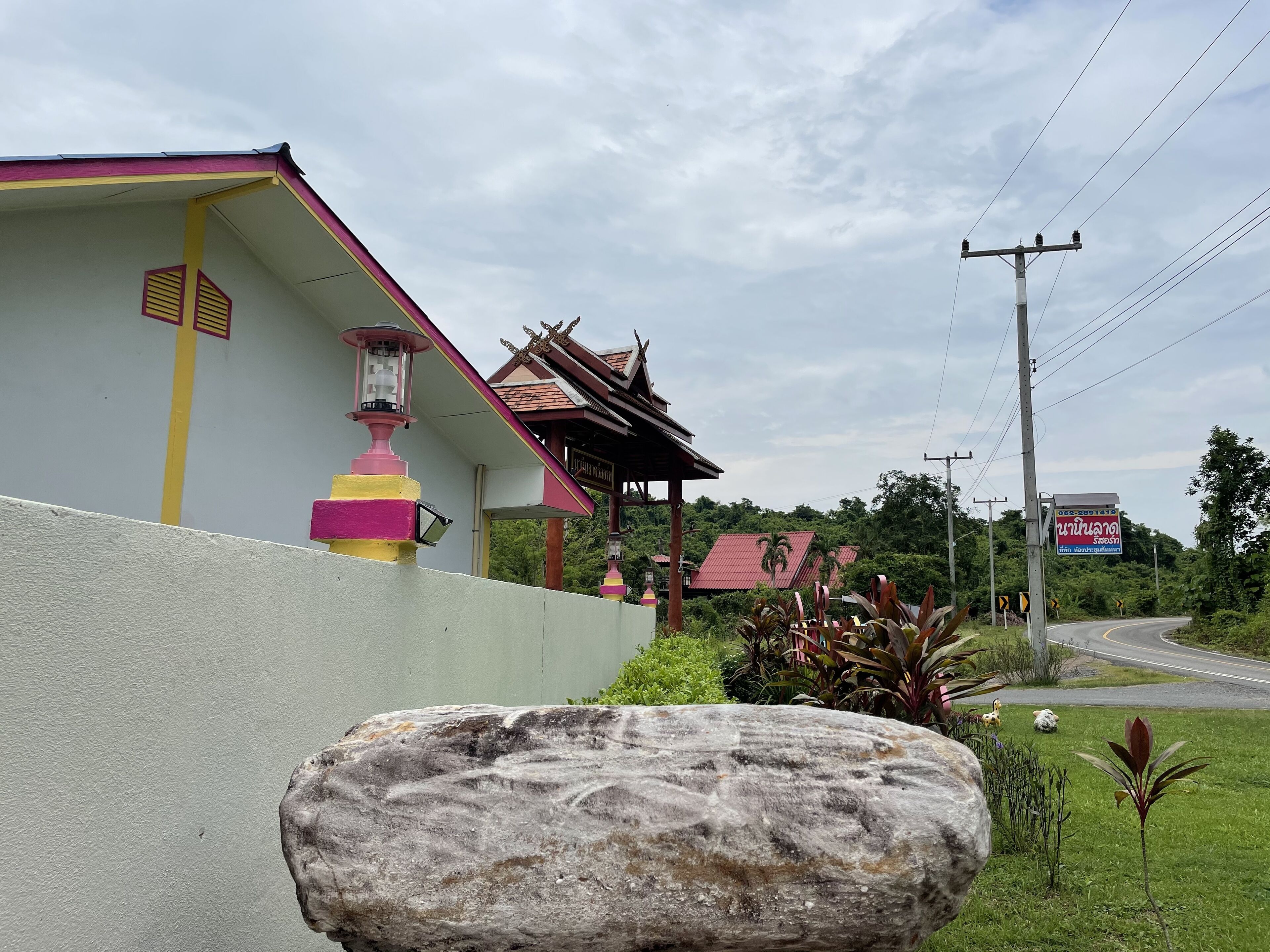 A building with a white exterior and a pink roof, featuring a traditional architectural style with a tiled roof and decorative elements.