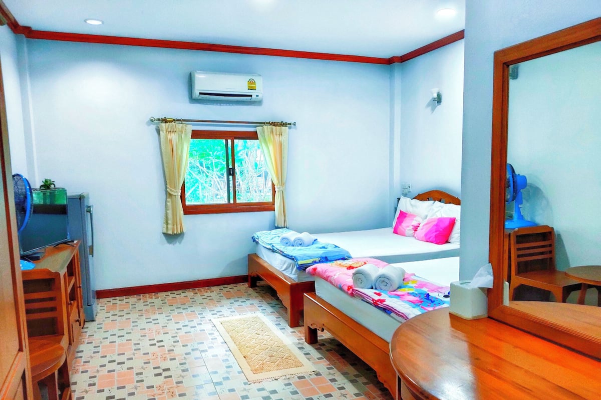 Un dormitorio con dos camas, un escritorio, una silla, un espejo y un aire acondicionado.