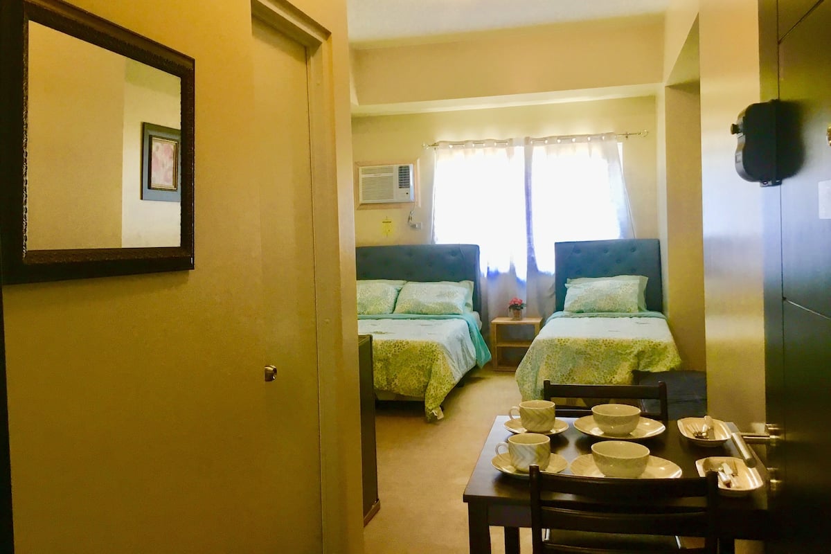 A room with two beds, a dining table with bowls and cups, and a mirror on the wall.