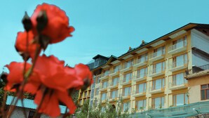 A multi-story hotel with balconies, a clear sky, and a garden area. - Primo Resorts (Manali)