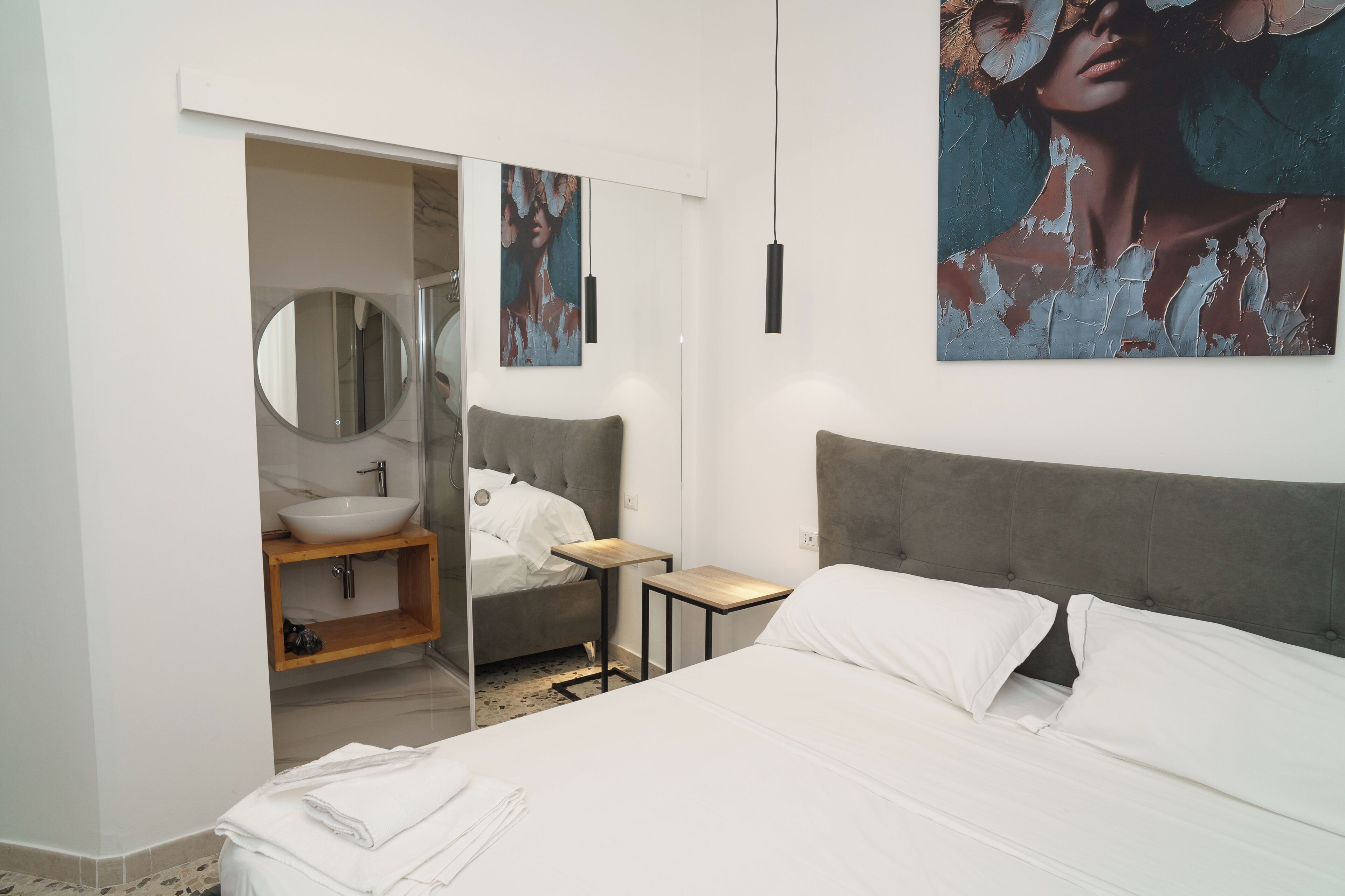 A bedroom with a bed, bedside table, and a large mirror.