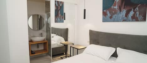 Un dormitorio con cama, mesita de noche y un espejo grande.