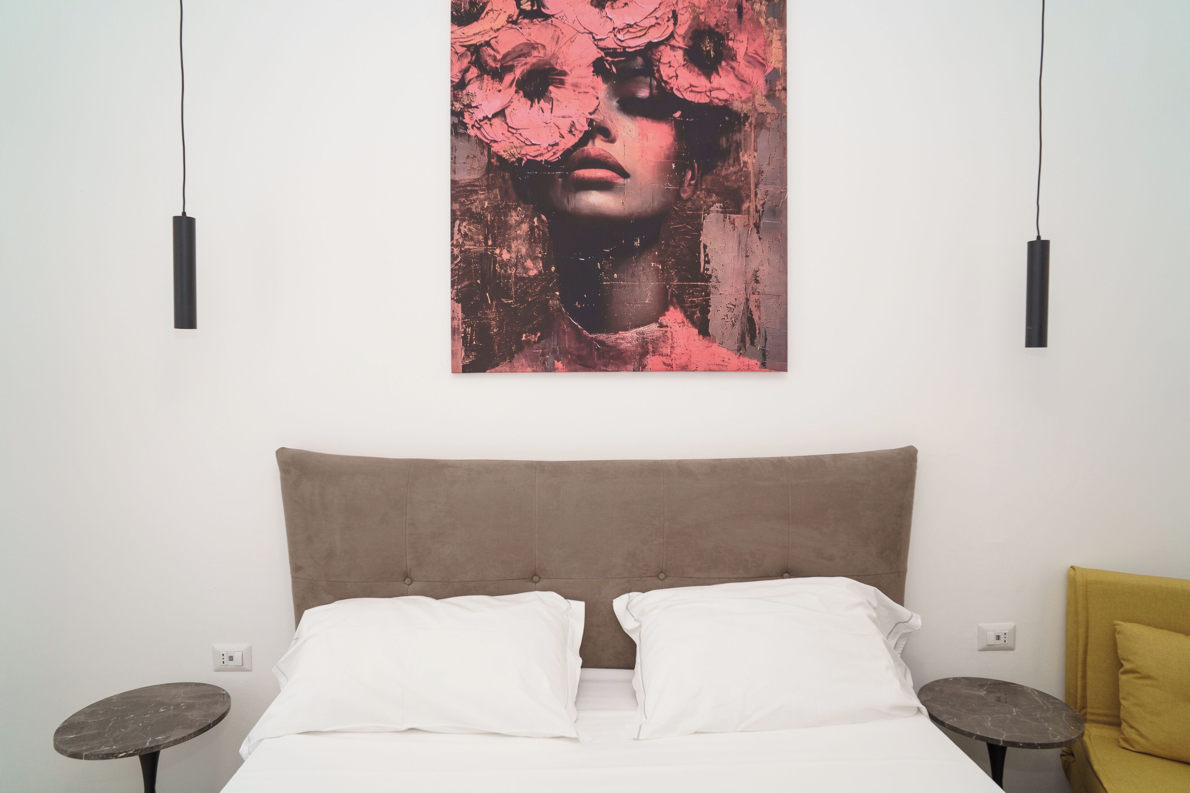A bedroom with a bed, two bedside tables, a bedside lamp, and a wall-mounted artwork.