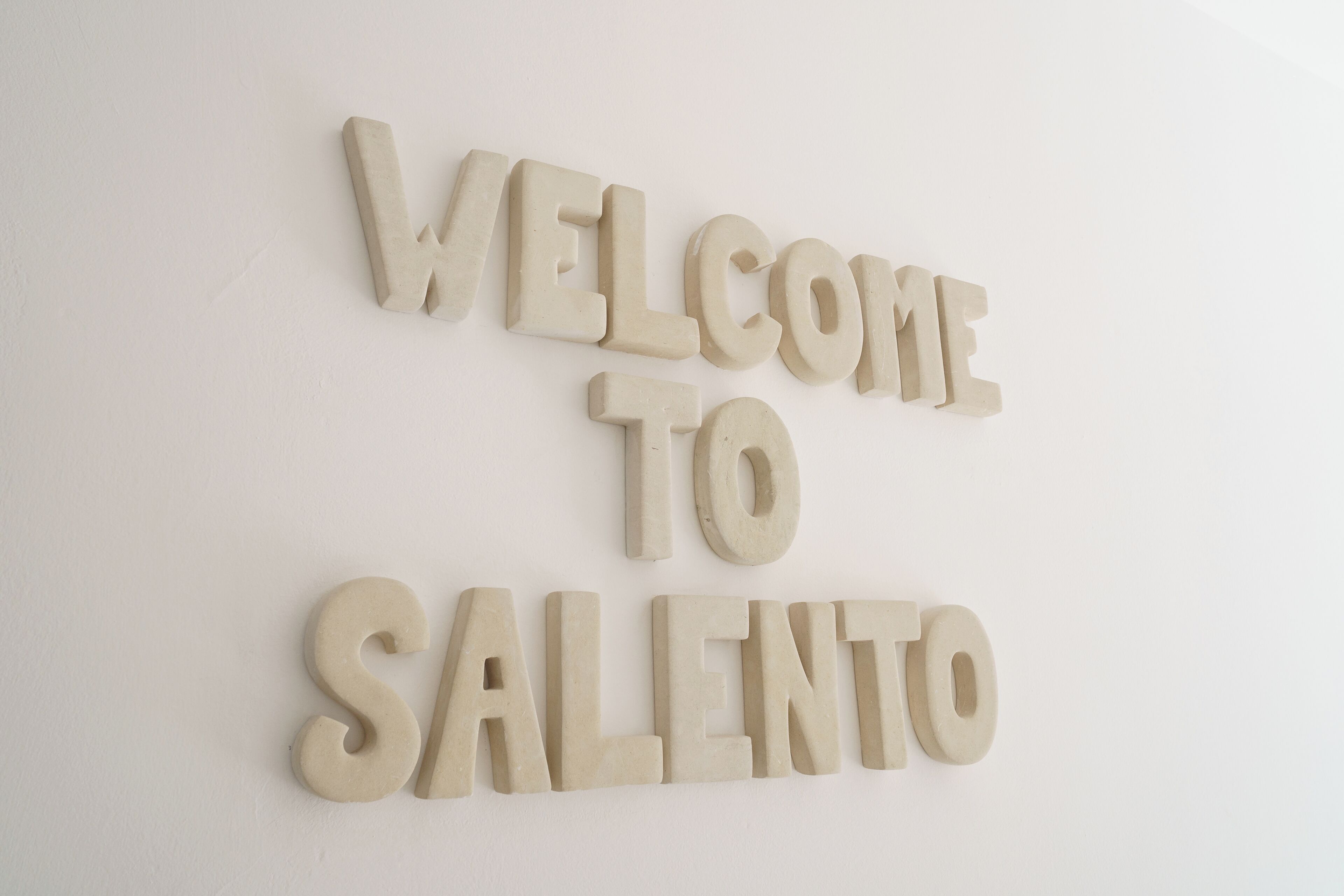 Un mur sur lequel est inscrit en grandes lettres le texte « BIENVENUE À SALENTO », dans une police simple et aux caractères bien définis.