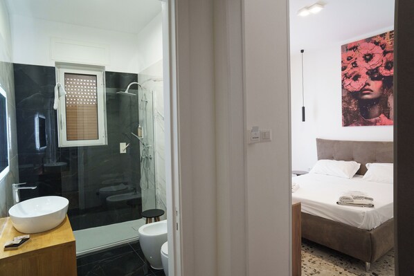 Un baño moderno con ducha envuelta en vidrio, un lavabo blanco y un inodoro.