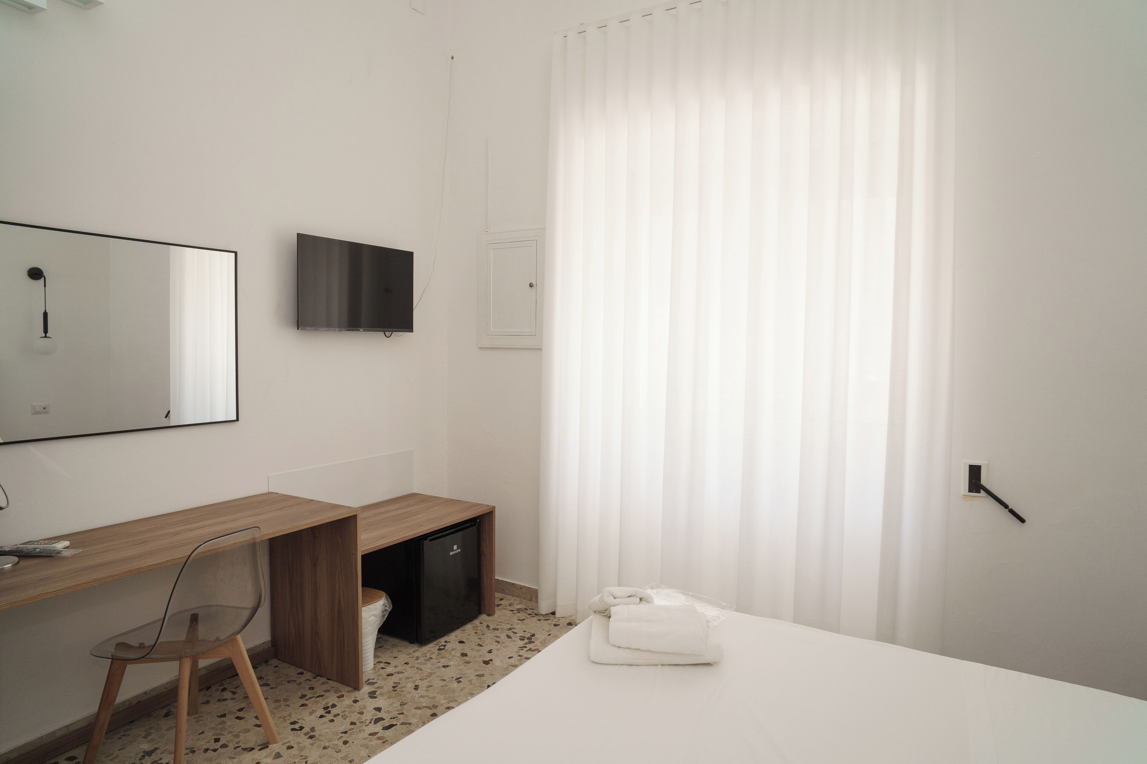 Ein Hotelzimmer mit Bett, Schreibtisch, Stuhl, Fernseher und Bad.