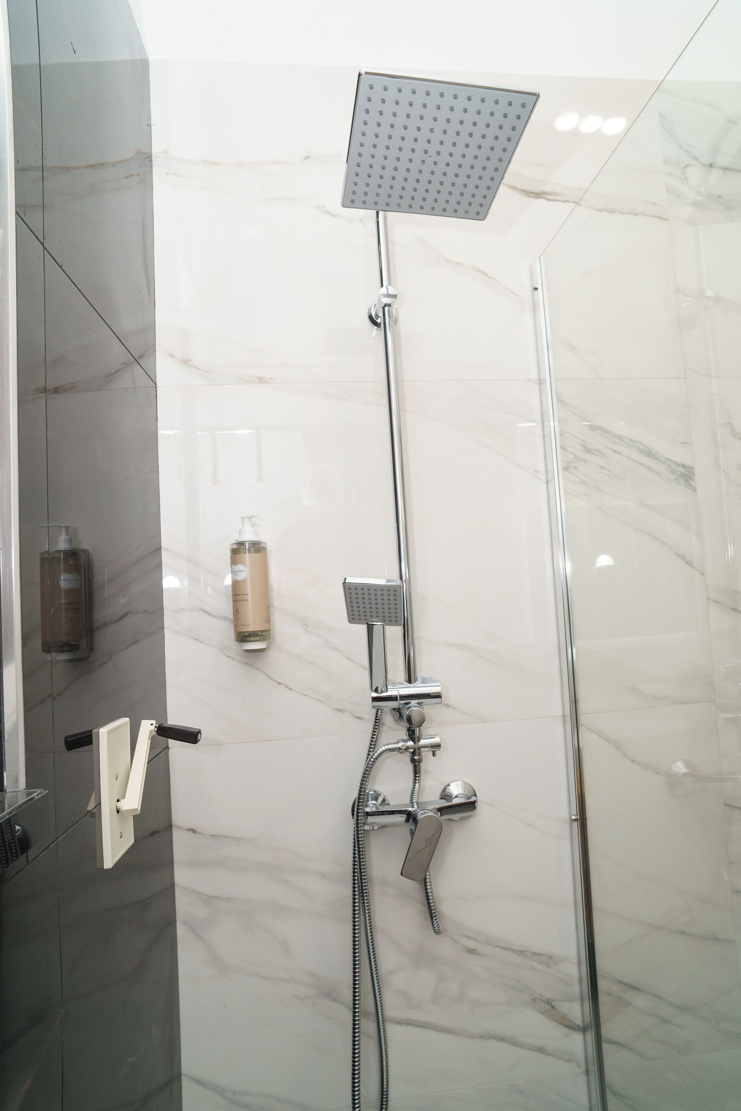 A modern bathroom with a shower, a hand dryer, and a soap dispenser.