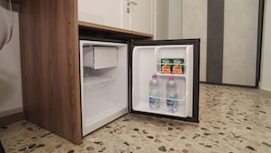Un petit réfrigérateur doté d’une porte en bois, contenant deux bouteilles d’eau et un pot de yaourt.