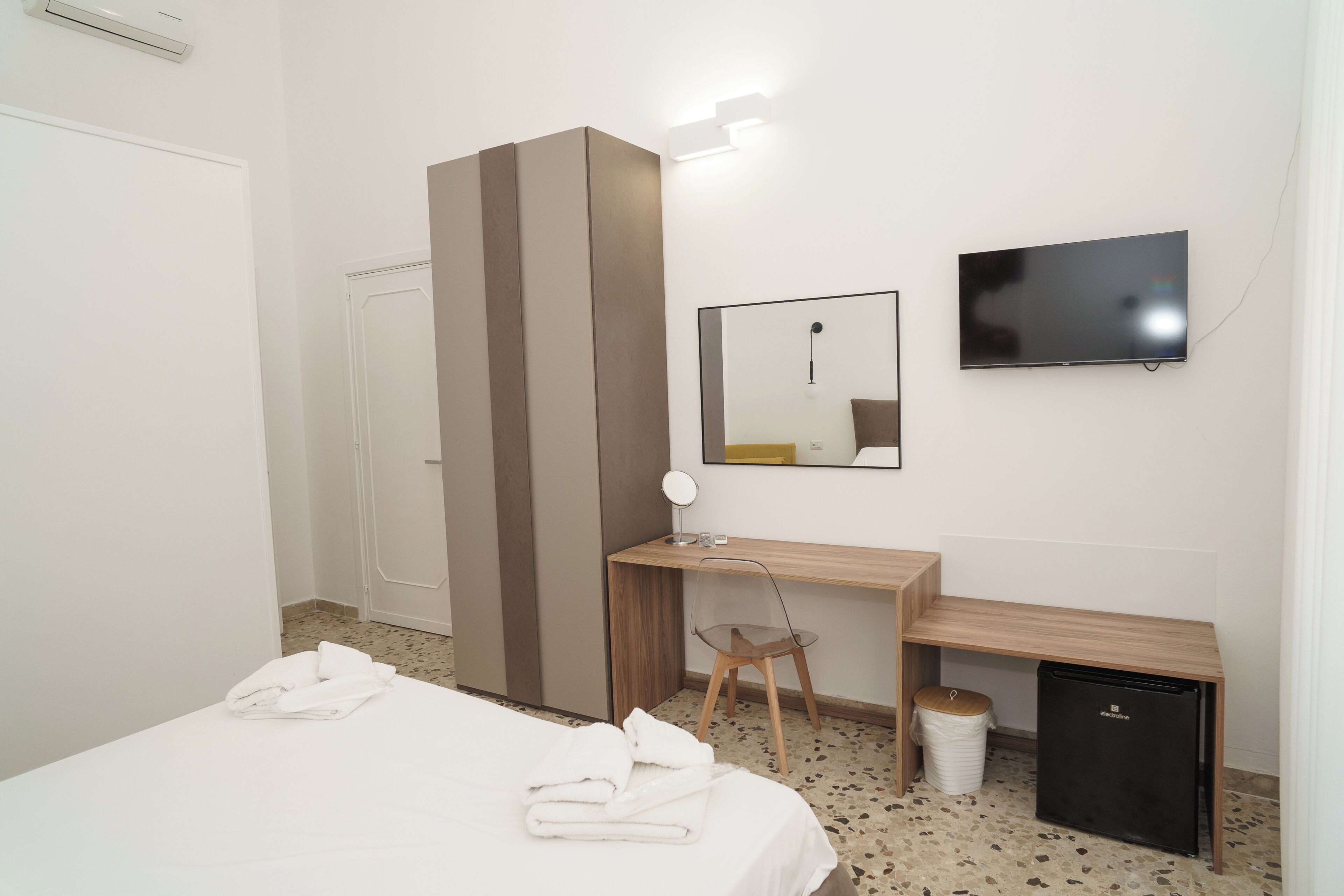 Une chambre d’hôtel équipée d’un lit, d’un bureau, d’une chaise, d’une télévision et d’un petit réfrigérateur.