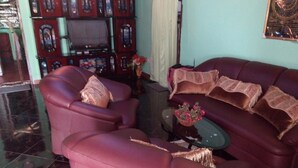 A living room with a red sofa, a matching armchair, and a small coffee table with a vase of flowers. - St Clair Holiday Home (Nuwara Eliya)