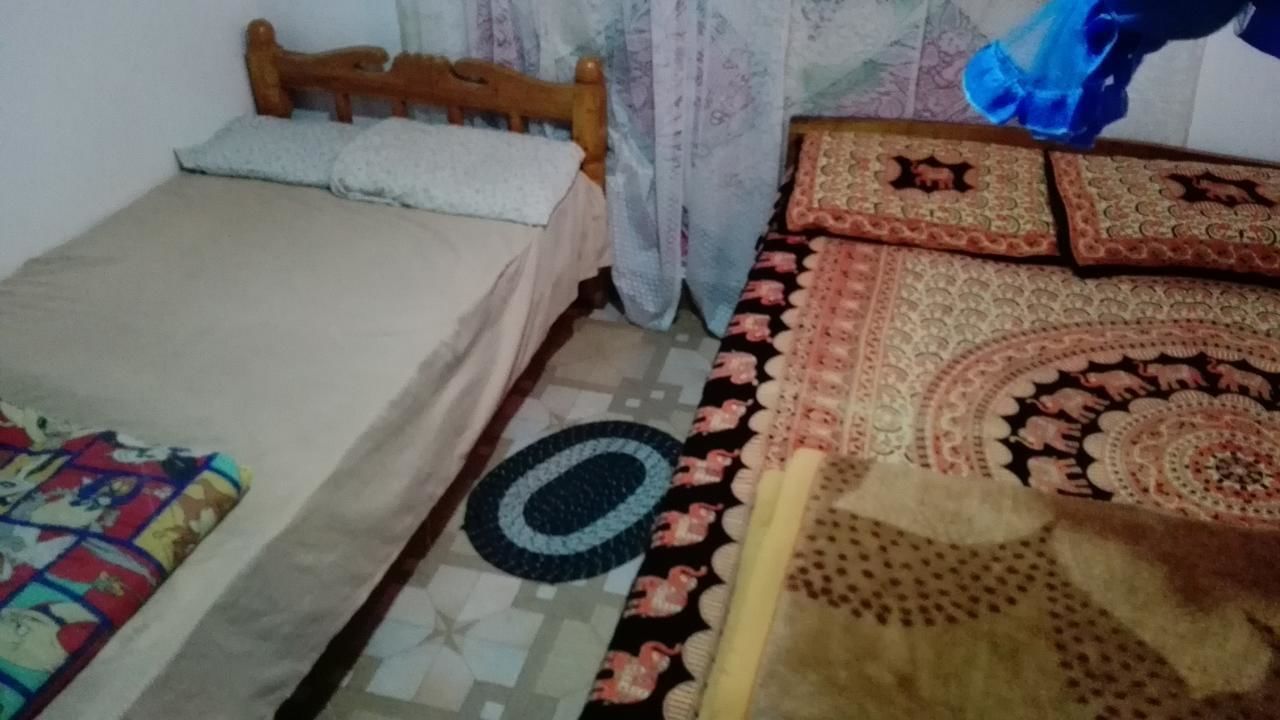 Un dormitorio con cama, cabecera de madera, alfombra estampada y almohada decorativa.
