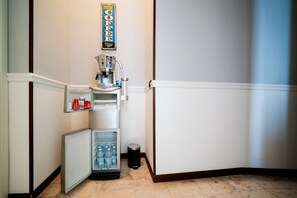 A compact kitchenette with a coffee machine, a mini-fridge, and a water dispenser.
