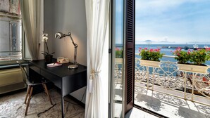 A balcony with a view of the sea, a desk with a lamp, and a chair. - Seaside Caracciolo (Naples)