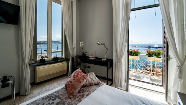 A bedroom with a large window, a desk, and a bed. - Seaside Caracciolo (Naples)