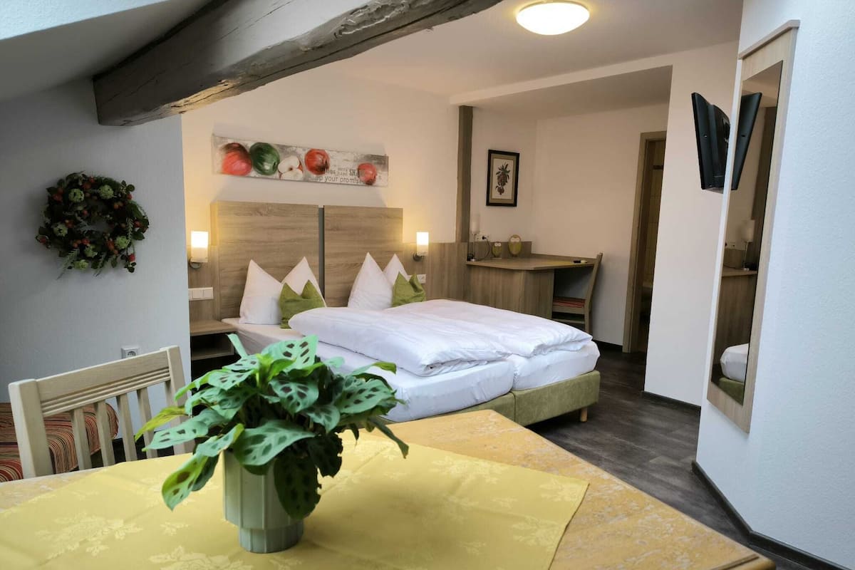 A cozy bedroom with a bed, bedside tables, a desk, and a potted plant.