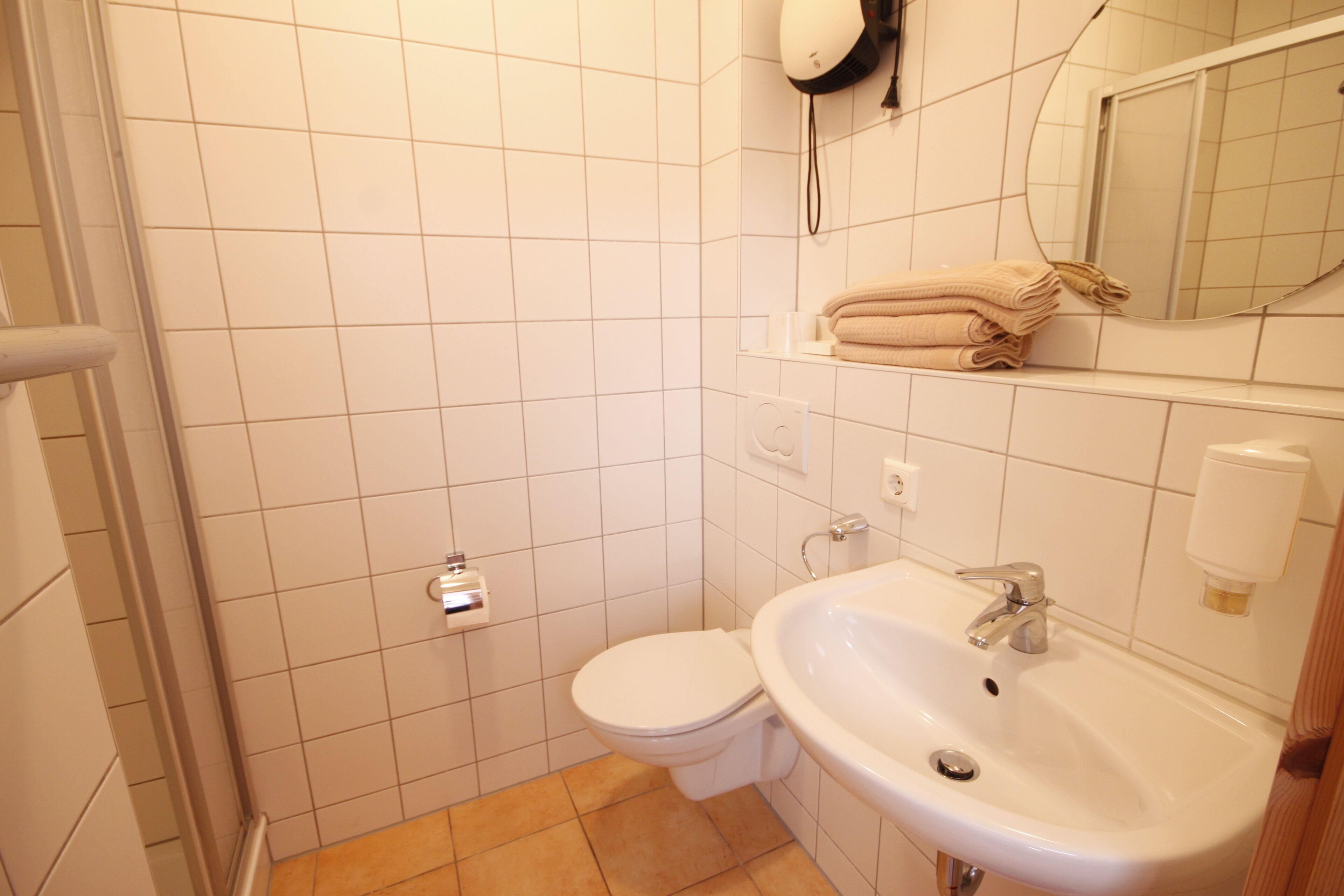 Een badkamer met toilet, wastafel en spiegel.