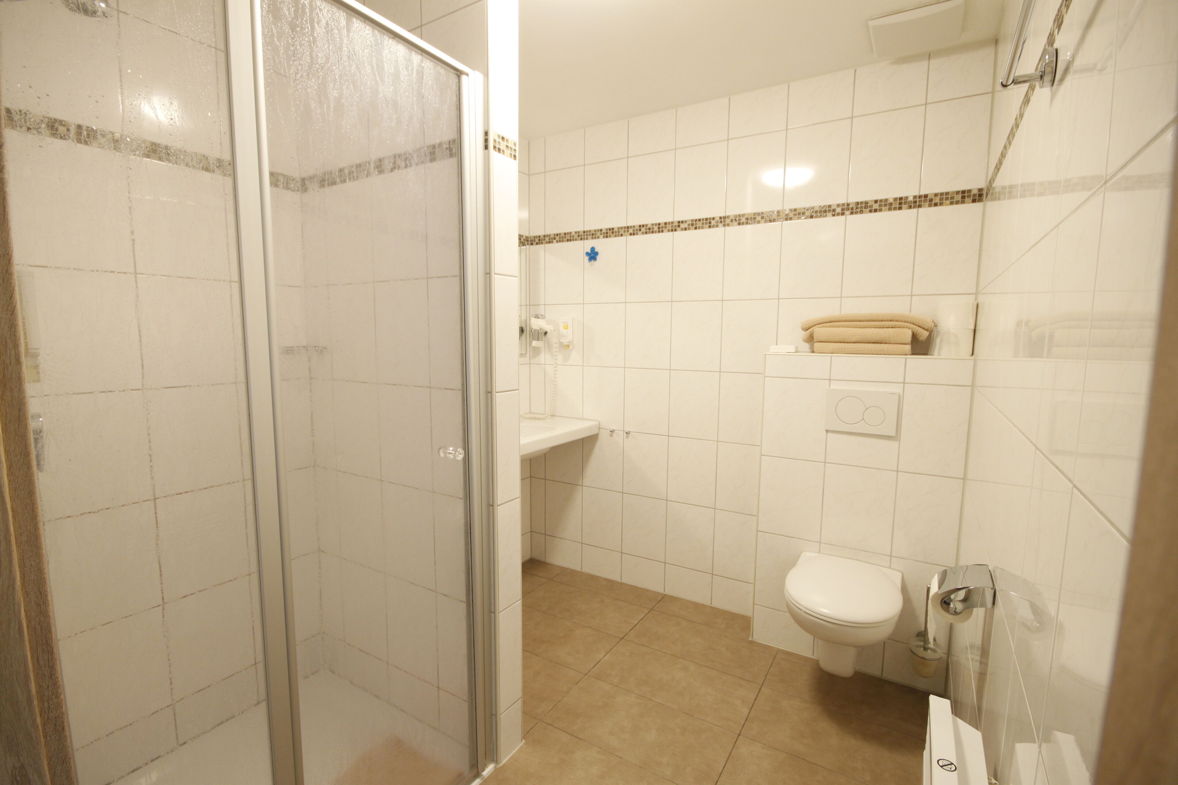 Un baño con cabina de ducha de vidrio, inodoro y lavamanos.
