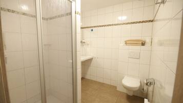 Un baño con cabina de ducha de vidrio, inodoro y lavamanos.