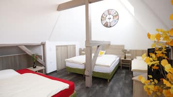 Un dormitorio con dos camas, una viga de techo de madera, un reloj y un florero con hojas amarillas.
