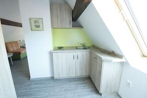 A compact kitchen with light wood cabinets, a green backsplash, and a window above the sink. - Am Treidelpfad (Hassmersheim)