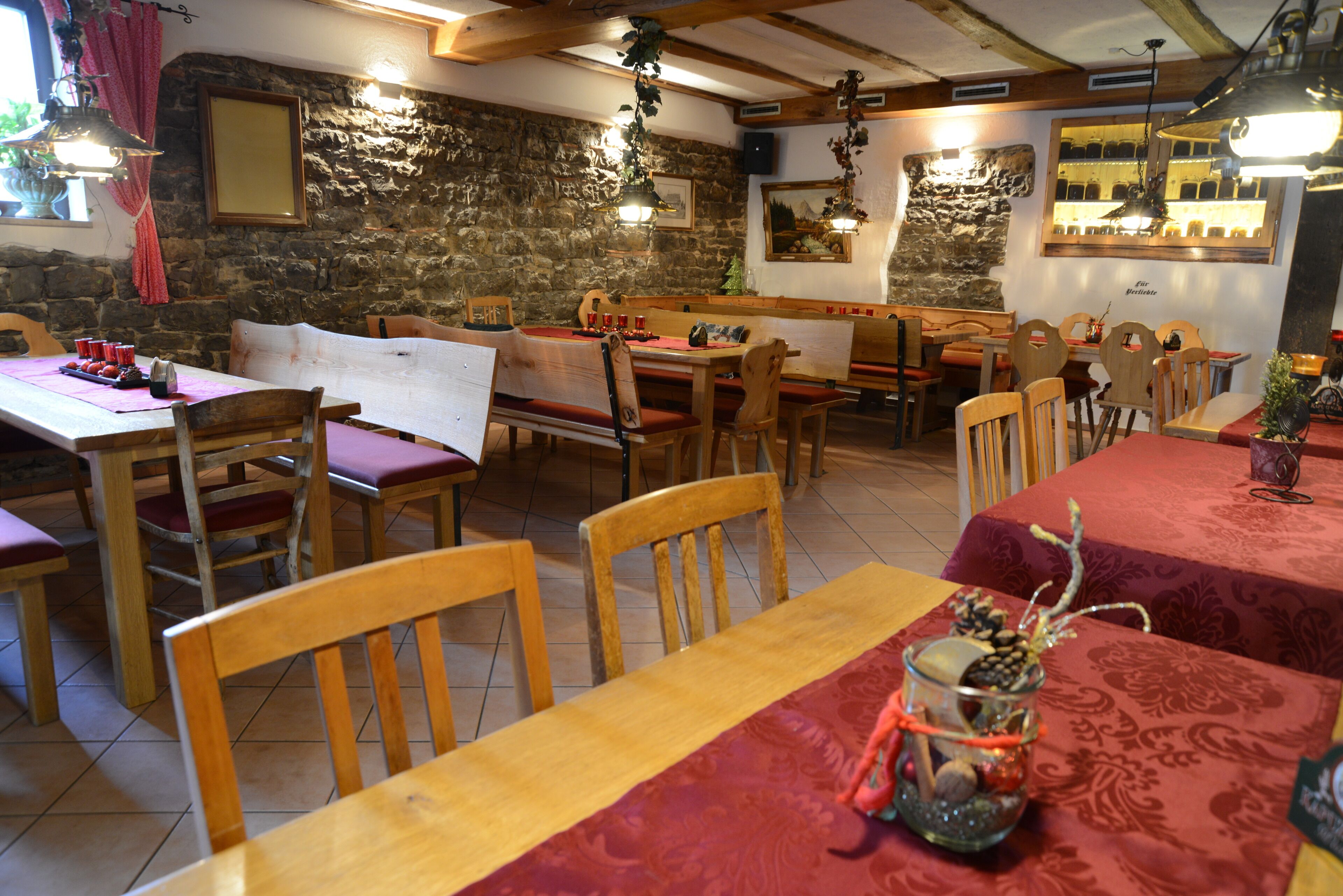 Un ristorante con tavoli e sedie in legno, pareti in pietra e piante sospese.