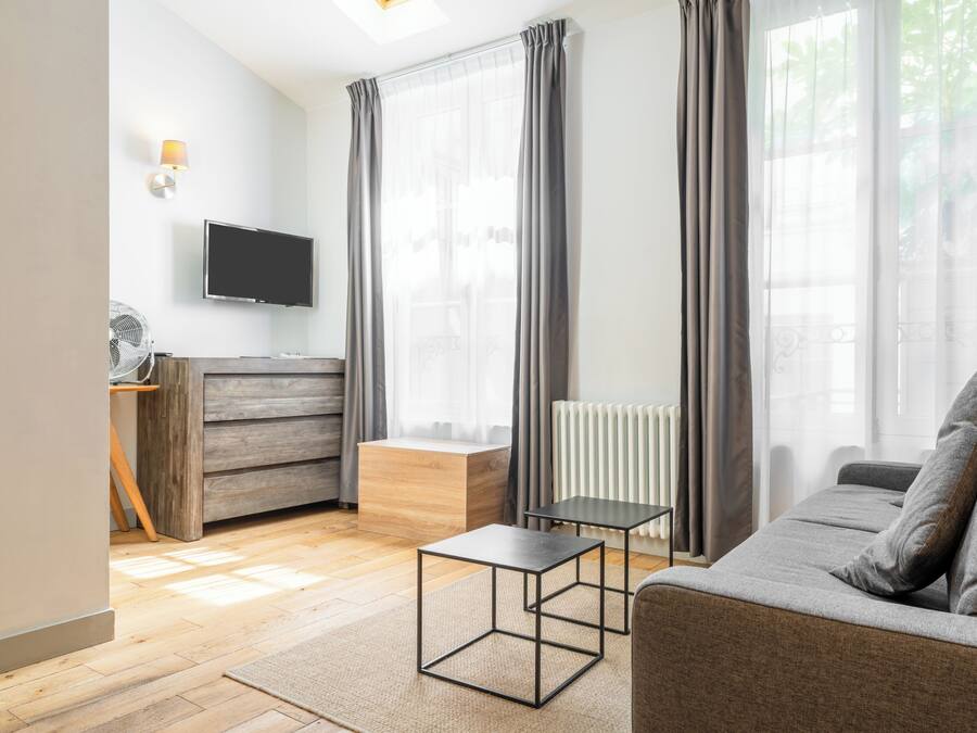 A modern living room with a sofa, a coffee table, a TV, a wooden cabinet, and a radiator.