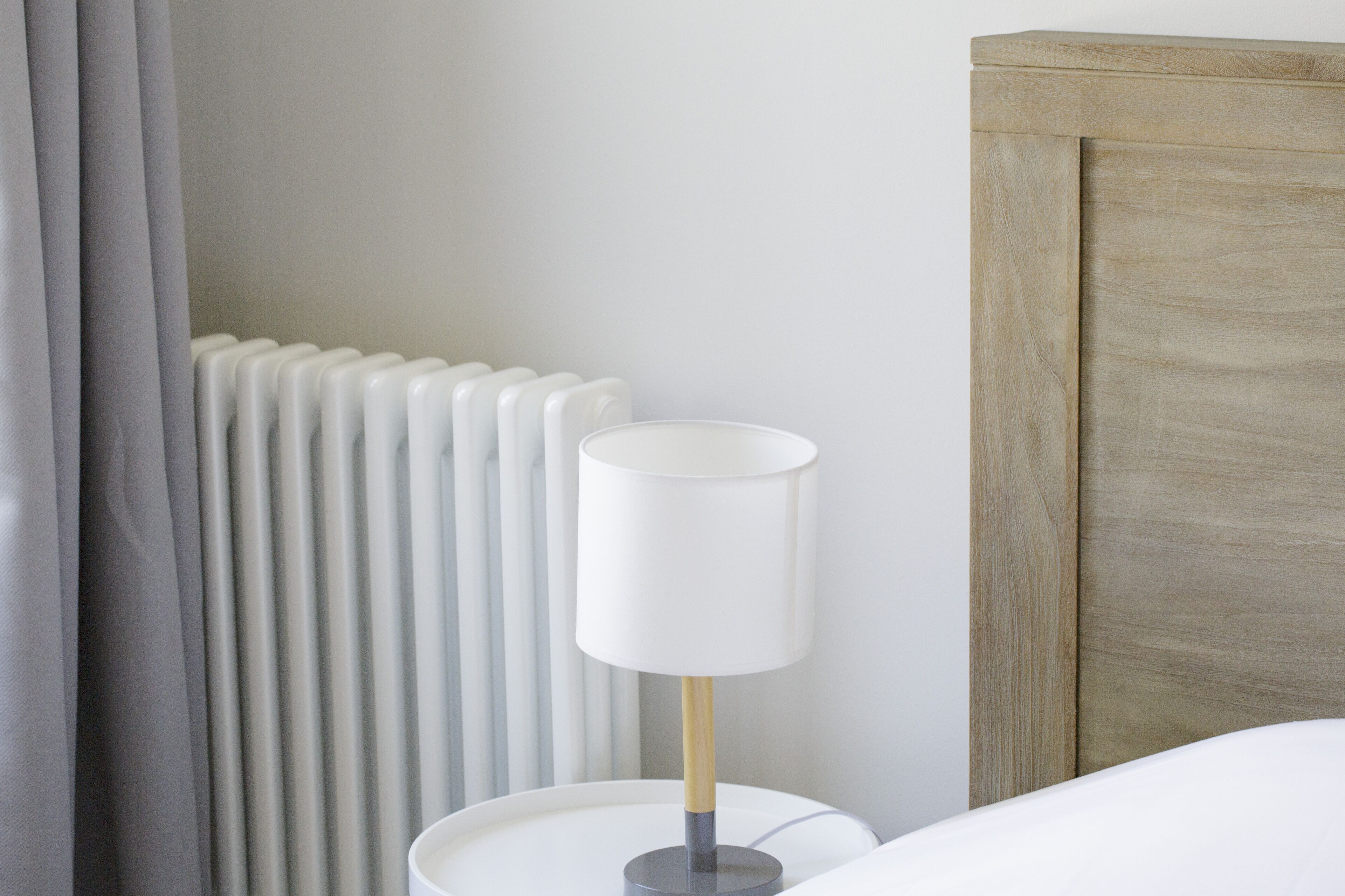 Et natbord med en lampe, en radiator og en træsengsramme.