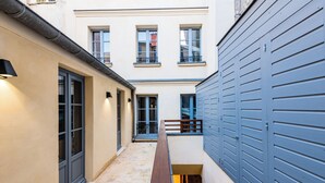 Une ruelle étroite avec un banc, une porte et un immeuble dont la porte de garage est bleue.