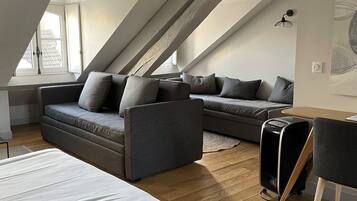 Une chambre de style loft avec un grand lit, deux canapés, une petite table et une valise.