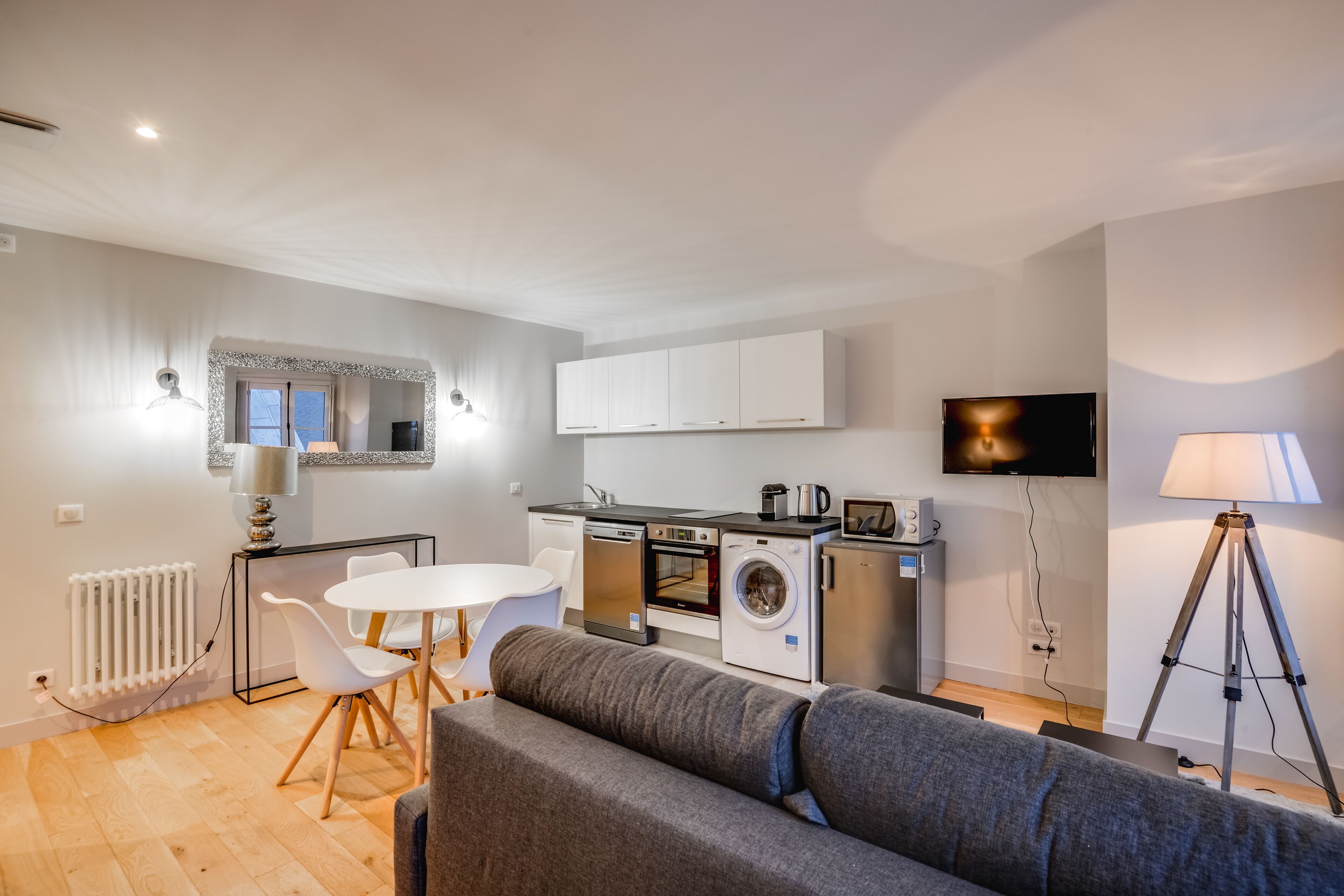 Une cuisine moderne avec des meubles blancs, un four encastré et un lave-linge.