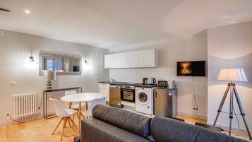 Une cuisine moderne avec des meubles blancs, un four encastré et un lave-linge.