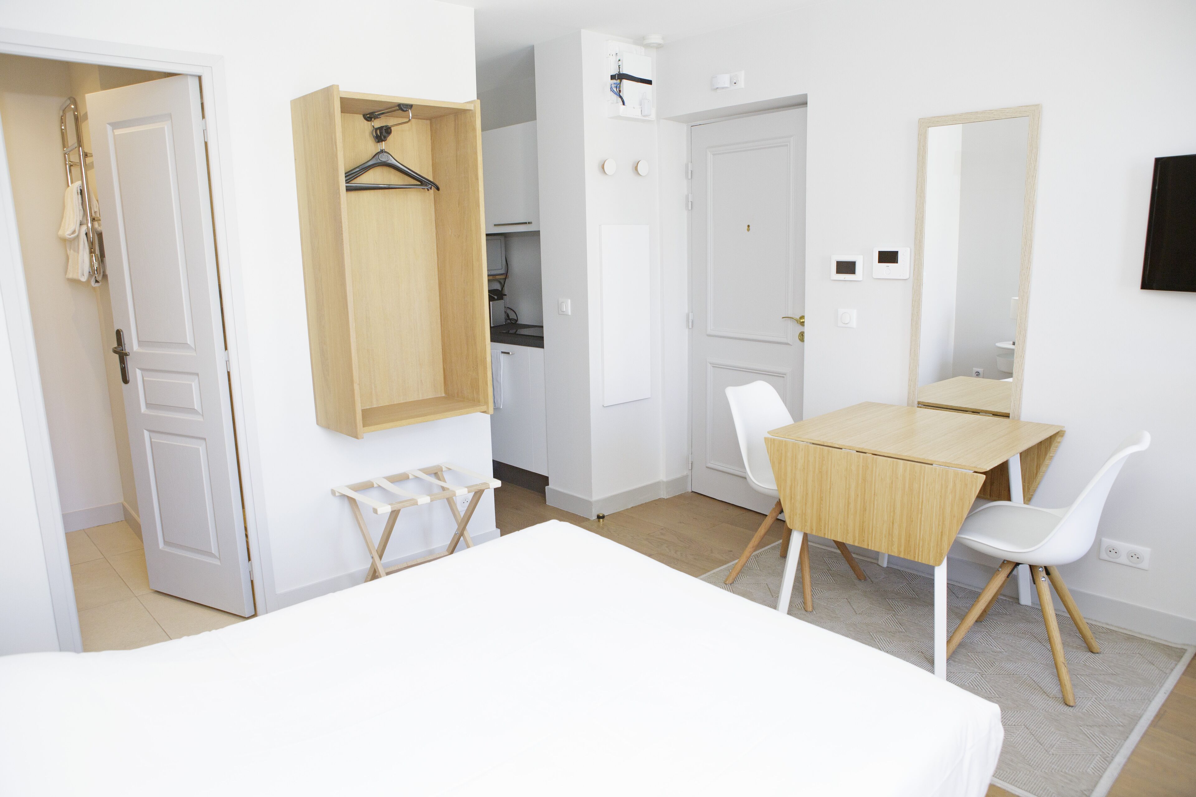 Une chambre d’hôtel comprenant un lit, un bureau, une chaise, une armoire et un miroir.