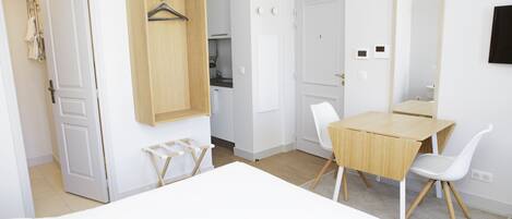 A hotel room with a bed, a desk, a chair, a wardrobe, and a mirror.
