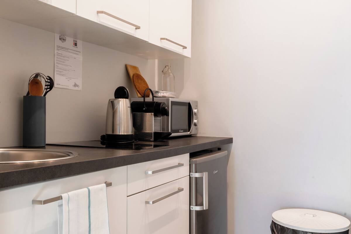 Une cuisine moderne avec des meubles blancs, un lave-vaisselle en acier inoxydable, un four à micro-ondes et un plancher en bois.
