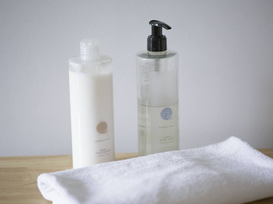 Deux bouteilles de savon liquide et une serviette blanche pliée, posées sur une surface en bois.