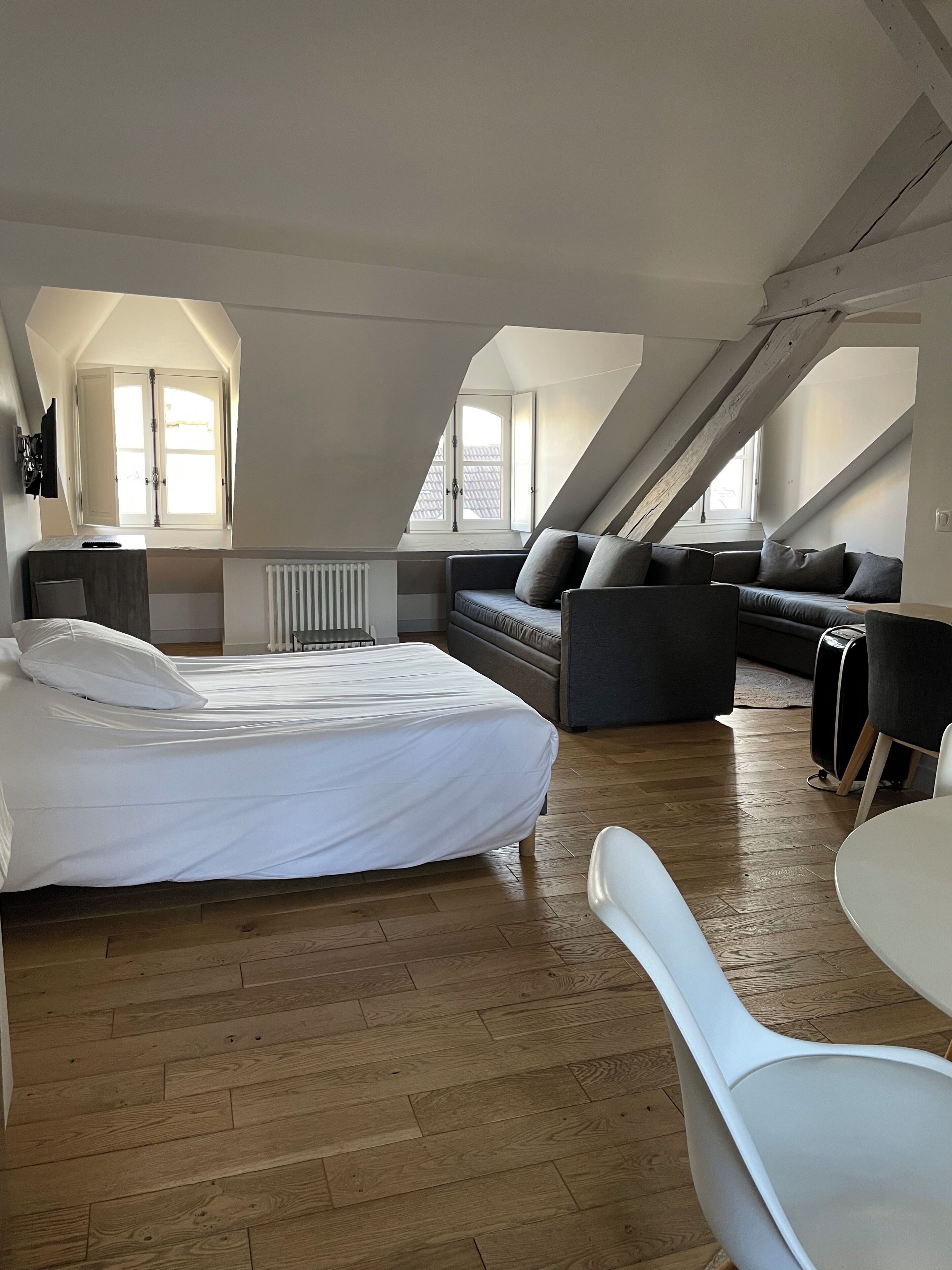 A modern loft bedroom with a large bed, a sofa, and a dining area.