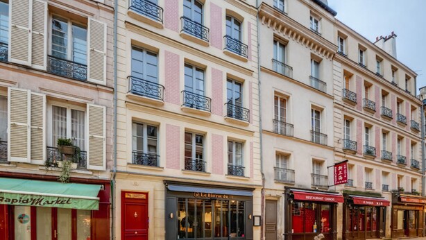 Une rangée de bâtiments de style européen, à plusieurs étages, présentant des éléments architecturaux traditionnels tels que des volets et des balcons.