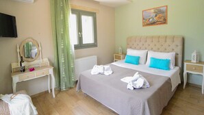 A hotel room with a bed, a dresser, a mirror, a window with curtains, a radiator, a painting on the wall, and a television mounted on the wall. - Villa Lobos (Zakynthos)
