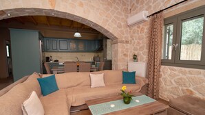 A cozy living room with a stone wall, a wooden coffee table, and a sofa with cushions. - Villa Lobos (Zakynthos)