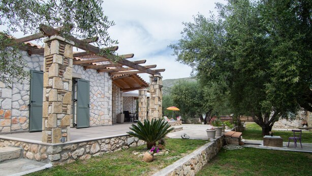 A stone building with a pergola, outdoor seating, and a well-maintained garden. - Villa Lobos (Zakynthos)