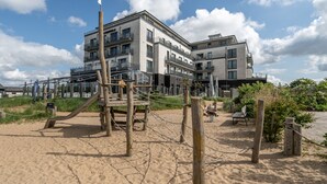 Un bâtiment moderne doté de nombreux balcons et d’une aire de jeux avec des structures en bois et des cordes.
