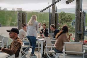 A group of people dining outdoors at a restaurant with a view of the hills. - Appartement Küstenperle (Büsum)