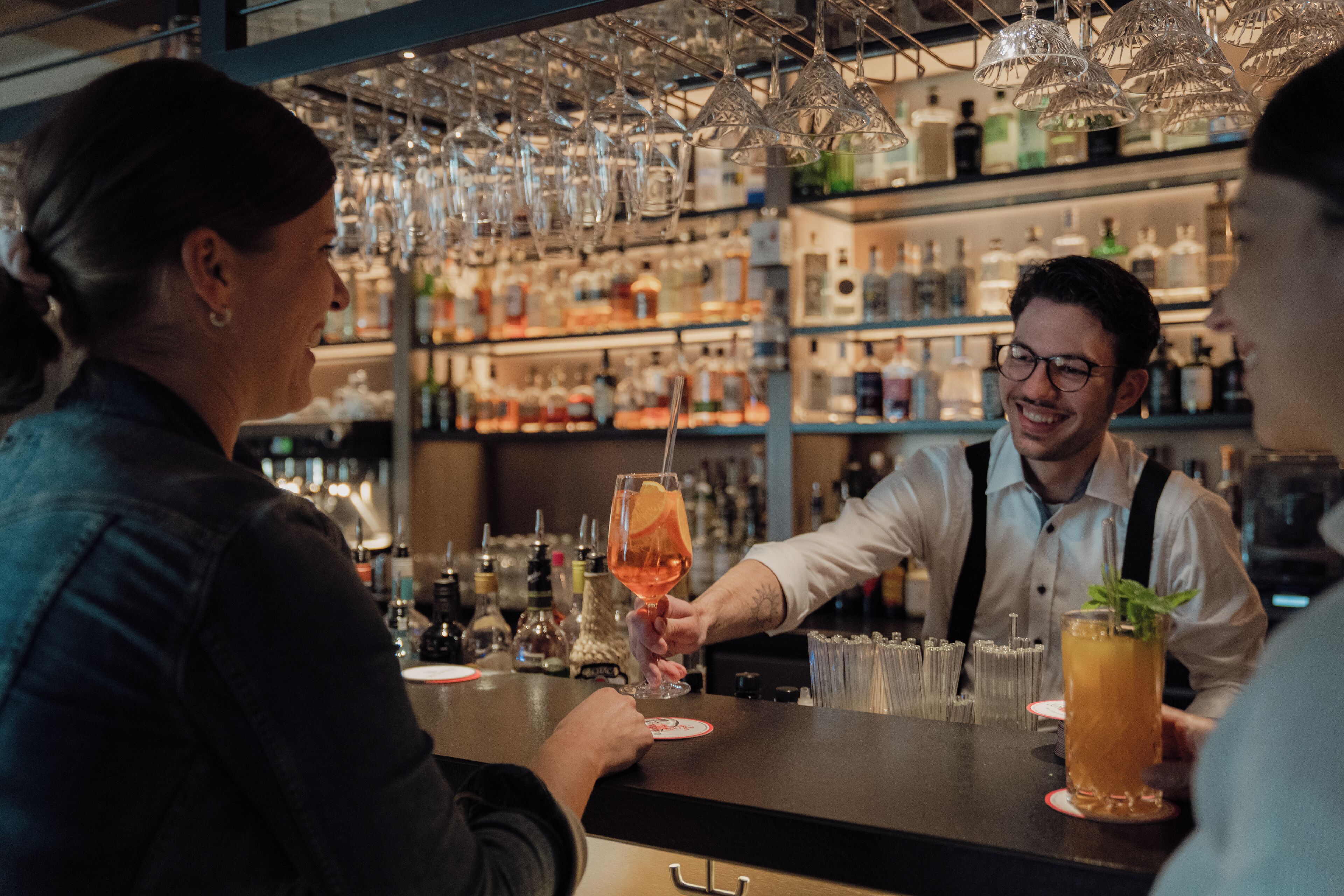 Un bar où un barman sert une boisson à un client.
