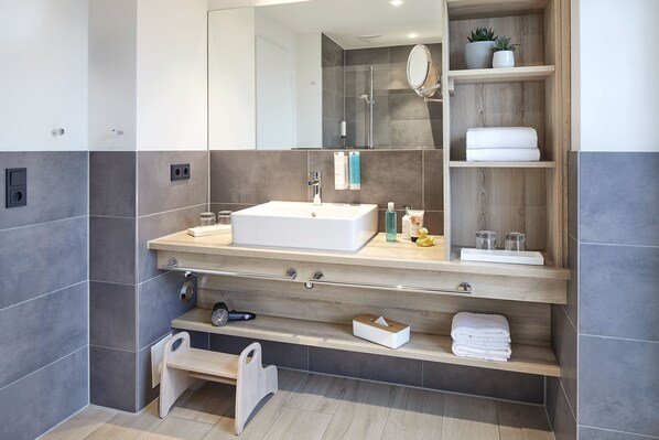 Un baño moderno con un espejo grande, un lavabo y una repisa con toallas.