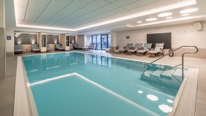 Une piscine avec des chaises longues et une entrée avec une porte vitrée.
