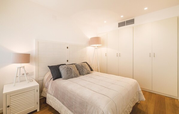 Un dormitorio con cama, mesita de noche, lámpara, armario y radiador.