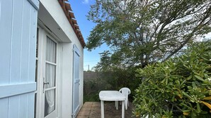 A small patio with a white table and chairs, a door, and a window.