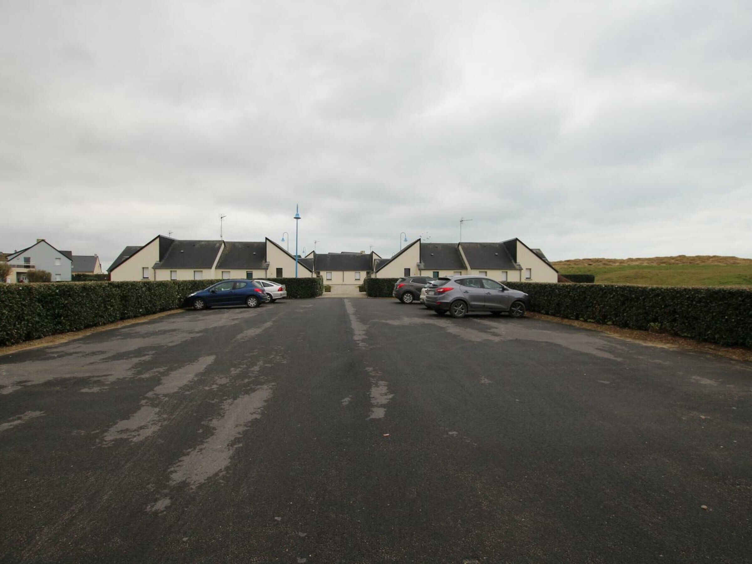 A parking lot with several cars parked in front of a row of houses.