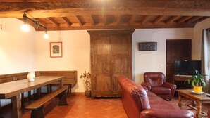 Una sala de estar acogedora con un banco de madera, un sofá de cuero y un televisor.